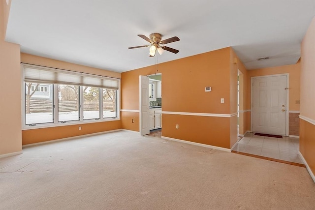 spare room featuring baseboards, carpet floors, visible vents, and a ceiling fan