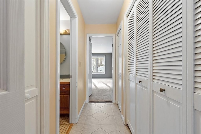 corridor featuring light tile patterned flooring and baseboards