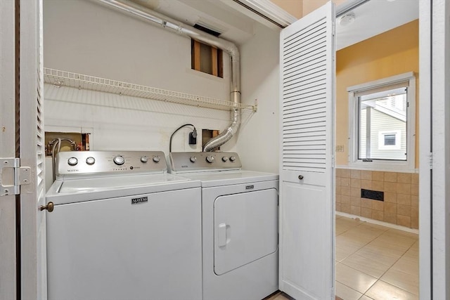 laundry area featuring laundry area, light tile patterned flooring, tile walls, and washer and dryer