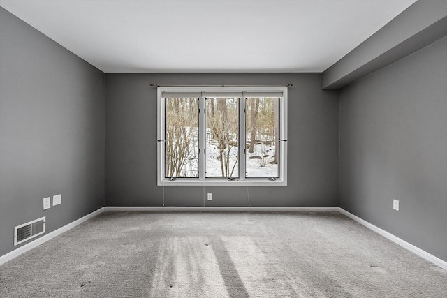 unfurnished room with carpet, visible vents, and baseboards