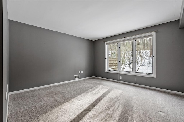 carpeted spare room featuring visible vents and baseboards