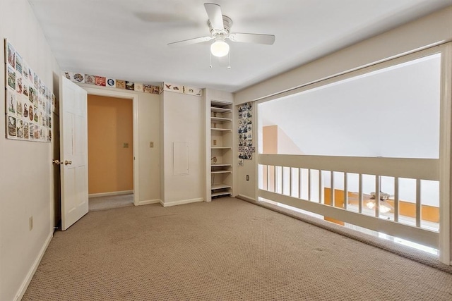 spare room featuring light carpet, ceiling fan, and baseboards