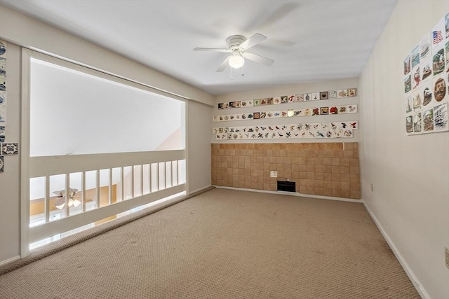 carpeted spare room featuring ceiling fan and baseboards