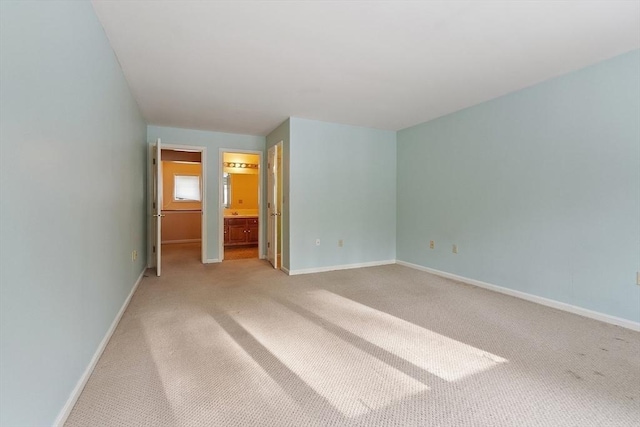 unfurnished bedroom with connected bathroom, light colored carpet, and baseboards