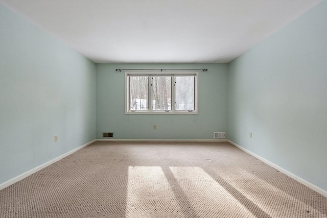 carpeted spare room with visible vents and baseboards