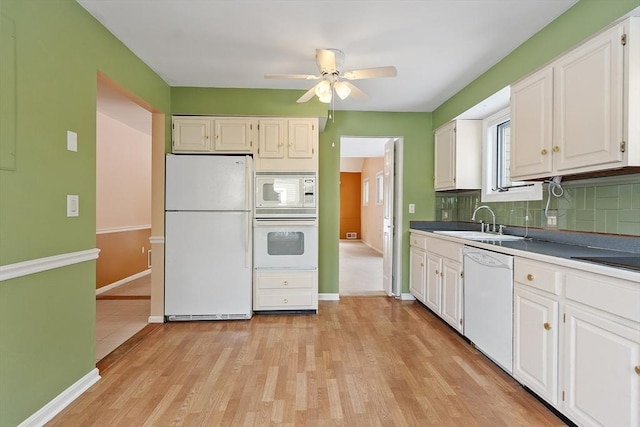 kitchen featuring white appliances, backsplash, white cabinets, and a sink