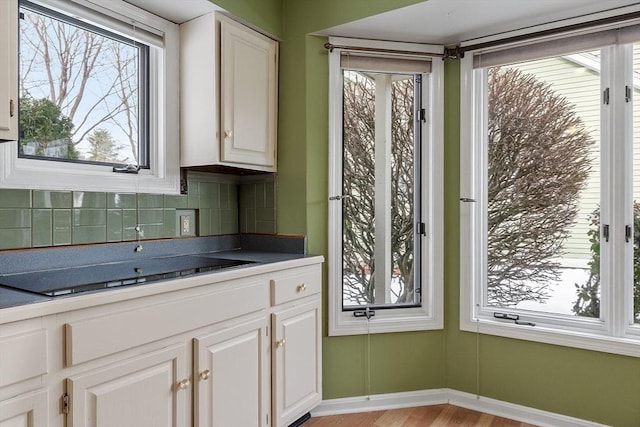 kitchen with light wood-style floors, baseboards, white cabinetry, and decorative backsplash