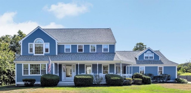 view of front facade with covered porch, a front lawn, and roof with shingles