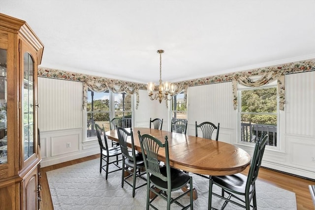 dining room featuring a decorative wall, wood finished floors, and a chandelier