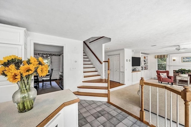 stairs featuring a textured ceiling, ceiling fan, built in features, and tile patterned floors