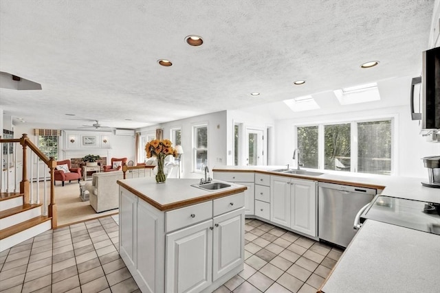 kitchen with light tile patterned floors, white cabinetry, stainless steel dishwasher, and a sink