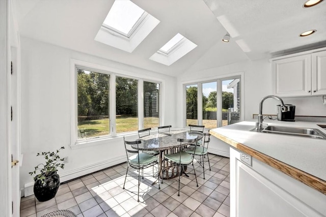 interior space featuring a baseboard heating unit, a sink, white cabinets, and a wealth of natural light