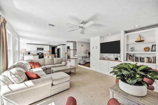 living area featuring stairway, a ceiling fan, recessed lighting, and light carpet