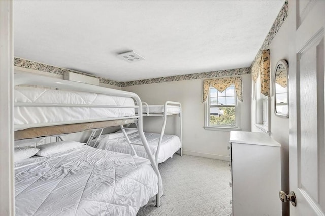 bedroom featuring light colored carpet, a textured ceiling, and baseboards