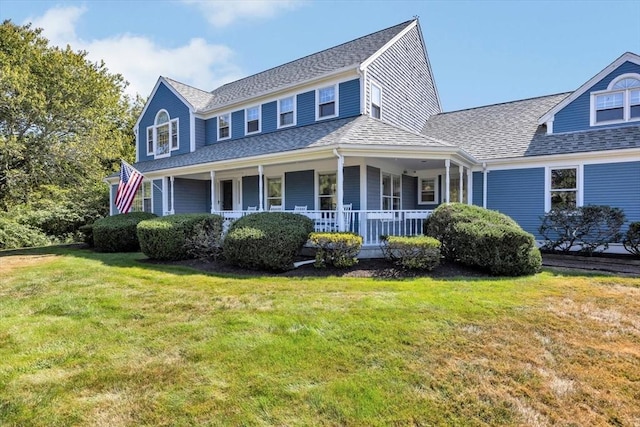 view of front facade featuring covered porch, a front yard, and roof with shingles