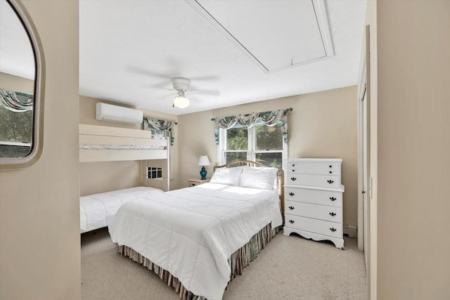 carpeted bedroom with attic access, ceiling fan, and a wall mounted air conditioner
