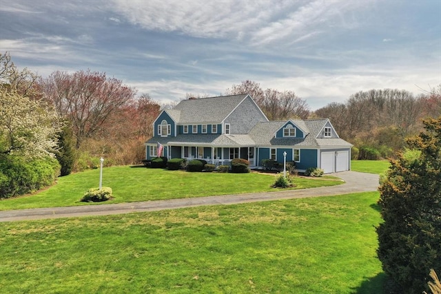 view of front of house featuring a porch, a front yard, driveway, and a garage