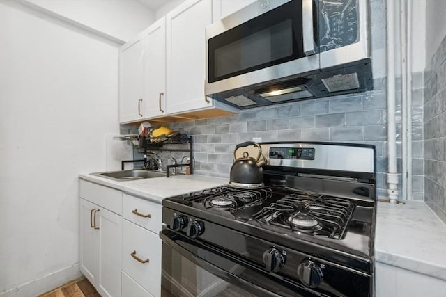 45-47 Crescent St, Swampscott, MA 01907 - kitchen with black gas range oven, stainless steel microwave, a sink, decorative backsplash, and white cabinetry