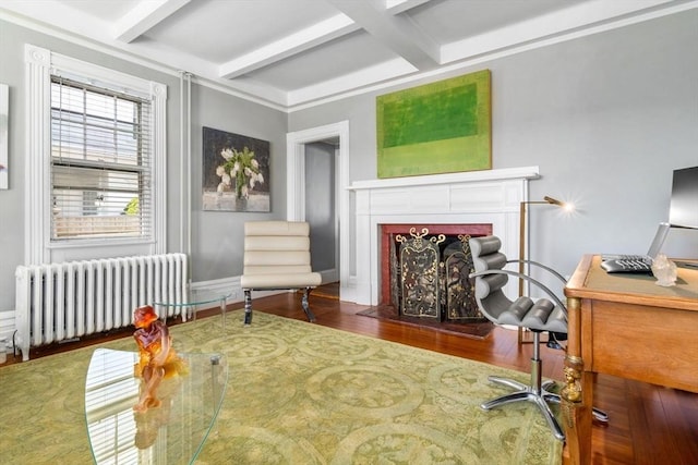 home office with radiator, beam ceiling, wood finished floors, coffered ceiling, and a fireplace with flush hearth