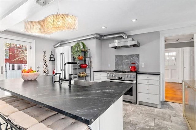 kitchen featuring a sink, wall chimney range hood, a wealth of natural light, and high end appliances