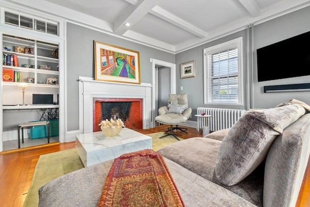 living area featuring coffered ceiling, radiator heating unit, wood finished floors, beamed ceiling, and a fireplace