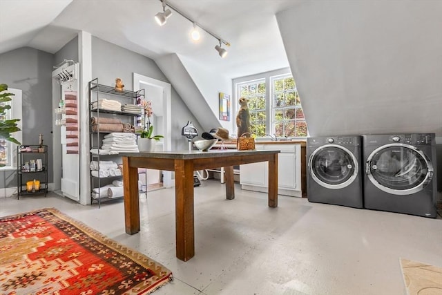 interior space featuring washer and dryer, rail lighting, vaulted ceiling, and a sink