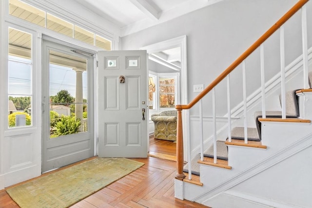 entrance foyer with stairs, beamed ceiling, and a healthy amount of sunlight