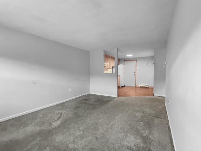 unfurnished living room with dark colored carpet, baseboard heating, and baseboards