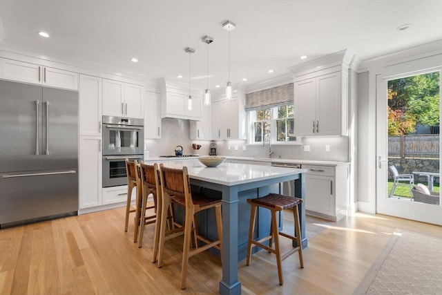 kitchen featuring white cabinets, appliances with stainless steel finishes, a breakfast bar, and light countertops