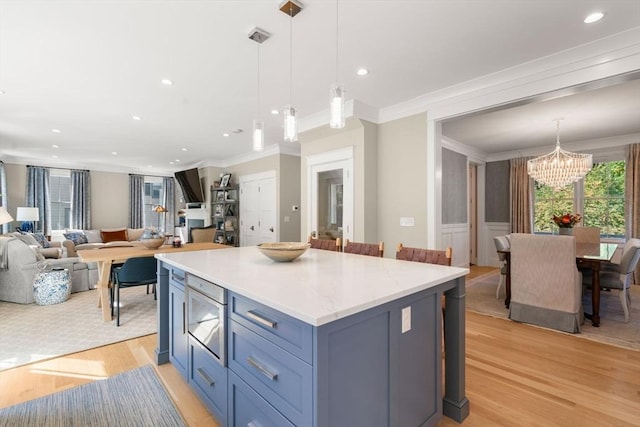 kitchen with a notable chandelier, open floor plan, light wood-type flooring, a center island, and crown molding