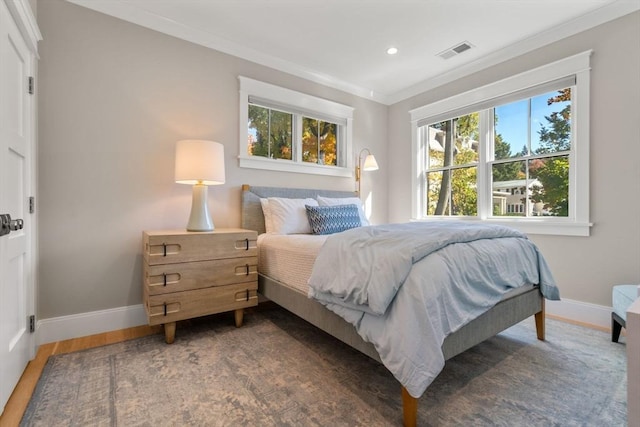 bedroom featuring baseboards, visible vents, wood finished floors, crown molding, and recessed lighting