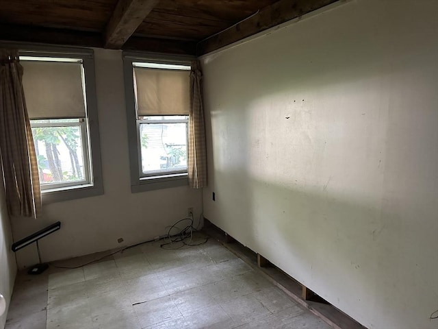 empty room featuring beam ceiling, wooden ceiling, and light floors