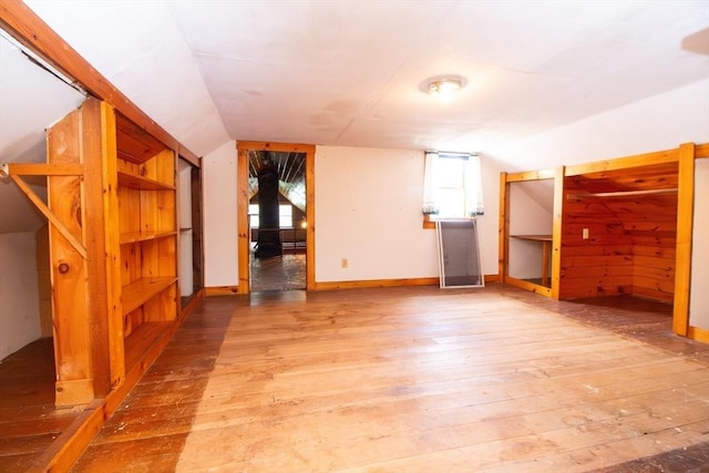 bonus room featuring vaulted ceiling, light wood finished floors, baseboard heating, and baseboards