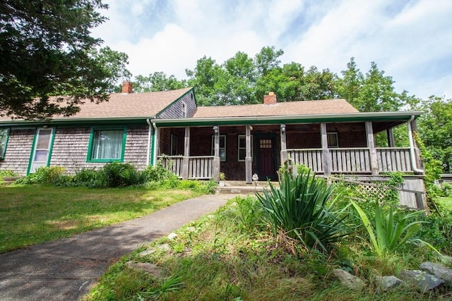 single story home featuring a porch, a shingled roof, a chimney, and a front lawn