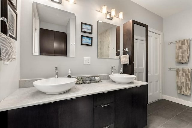 bathroom with double vanity, baseboards, and tile patterned flooring