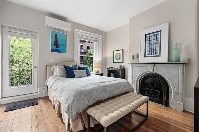 bedroom with an AC wall unit, multiple windows, wood-type flooring, and a fireplace