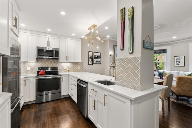 kitchen with stainless steel appliances, a sink, a peninsula, backsplash, and dark wood-style flooring