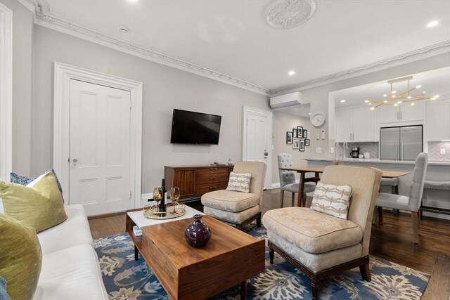 living room with a wall unit AC, recessed lighting, wood finished floors, ornamental molding, and baseboards