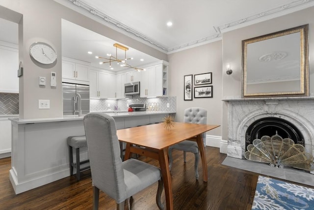 dining room featuring dark wood-style floors, ornamental molding, recessed lighting, baseboards, and a chandelier
