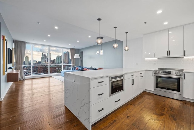 kitchen featuring white cabinetry, decorative backsplash, expansive windows, kitchen peninsula, and electric stove