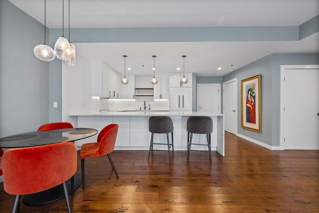 kitchen featuring white cabinetry, a kitchen bar, kitchen peninsula, and hanging light fixtures