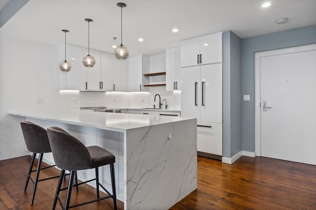 kitchen featuring dark hardwood / wood-style floors, decorative light fixtures, white cabinetry, sink, and decorative backsplash