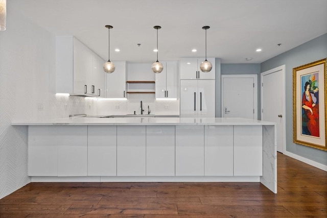 kitchen with decorative light fixtures, kitchen peninsula, white cabinets, and built in refrigerator