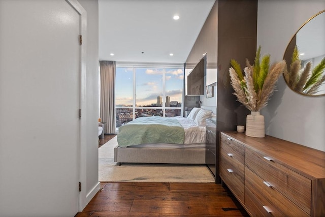 bedroom featuring expansive windows, dark hardwood / wood-style floors, and access to outside