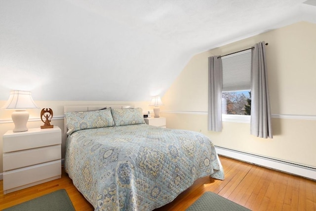 bedroom featuring a baseboard heating unit, wood-type flooring, and lofted ceiling