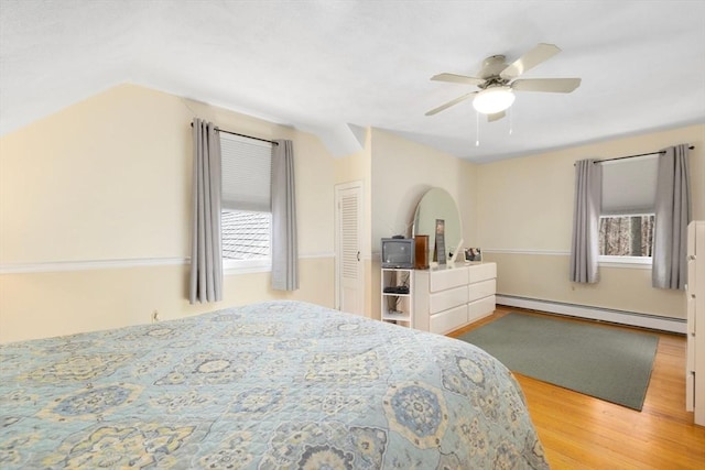 bedroom featuring a baseboard heating unit, wood finished floors, a ceiling fan, and vaulted ceiling