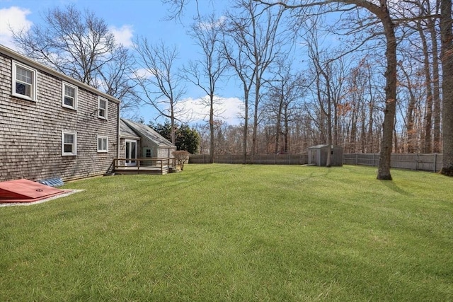 view of yard featuring a deck, an outbuilding, a storage unit, and a fenced backyard