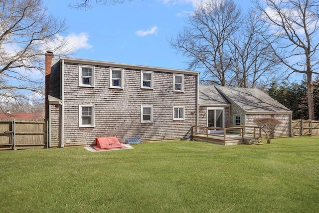 back of house with a wooden deck, a lawn, a fenced backyard, and a chimney