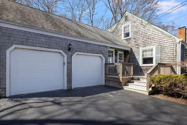 view of front of property with aphalt driveway, a chimney, a shingled roof, and an attached garage