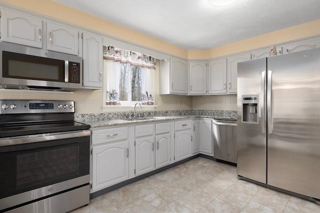 kitchen featuring a sink, stainless steel appliances, light stone countertops, and decorative backsplash